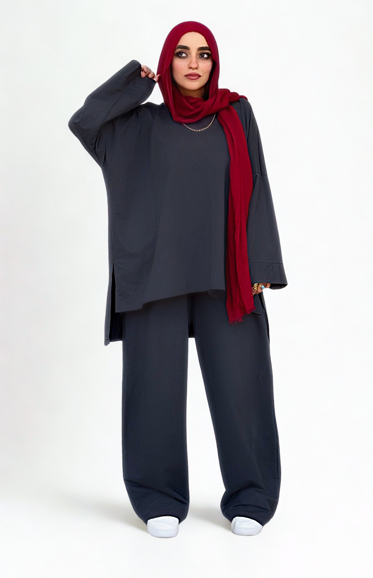 Woman wearing a gray outfit with a red hijab on a white background