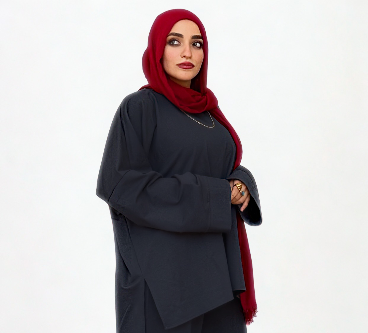 Woman wearing a dark outfit with a red hijab on a white background