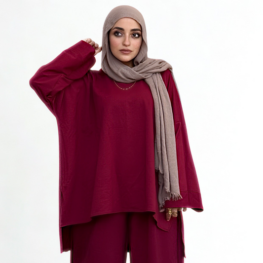Woman wearing a burgundy outfit with a beige hijab on a white background